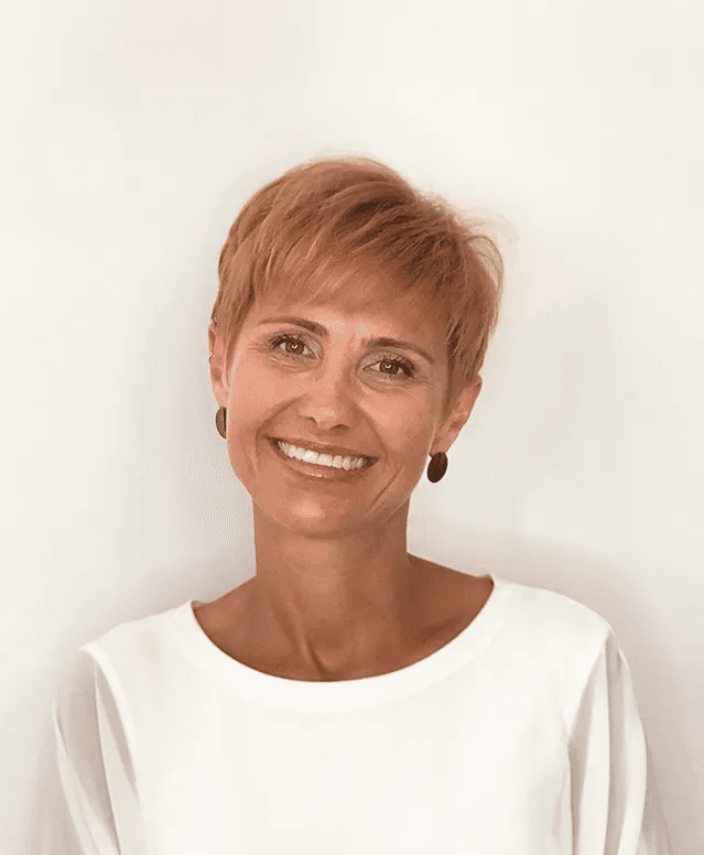 Dorota Hedzelek, PhD, registered clinical counsellor, smiling in a white top against a light wall.