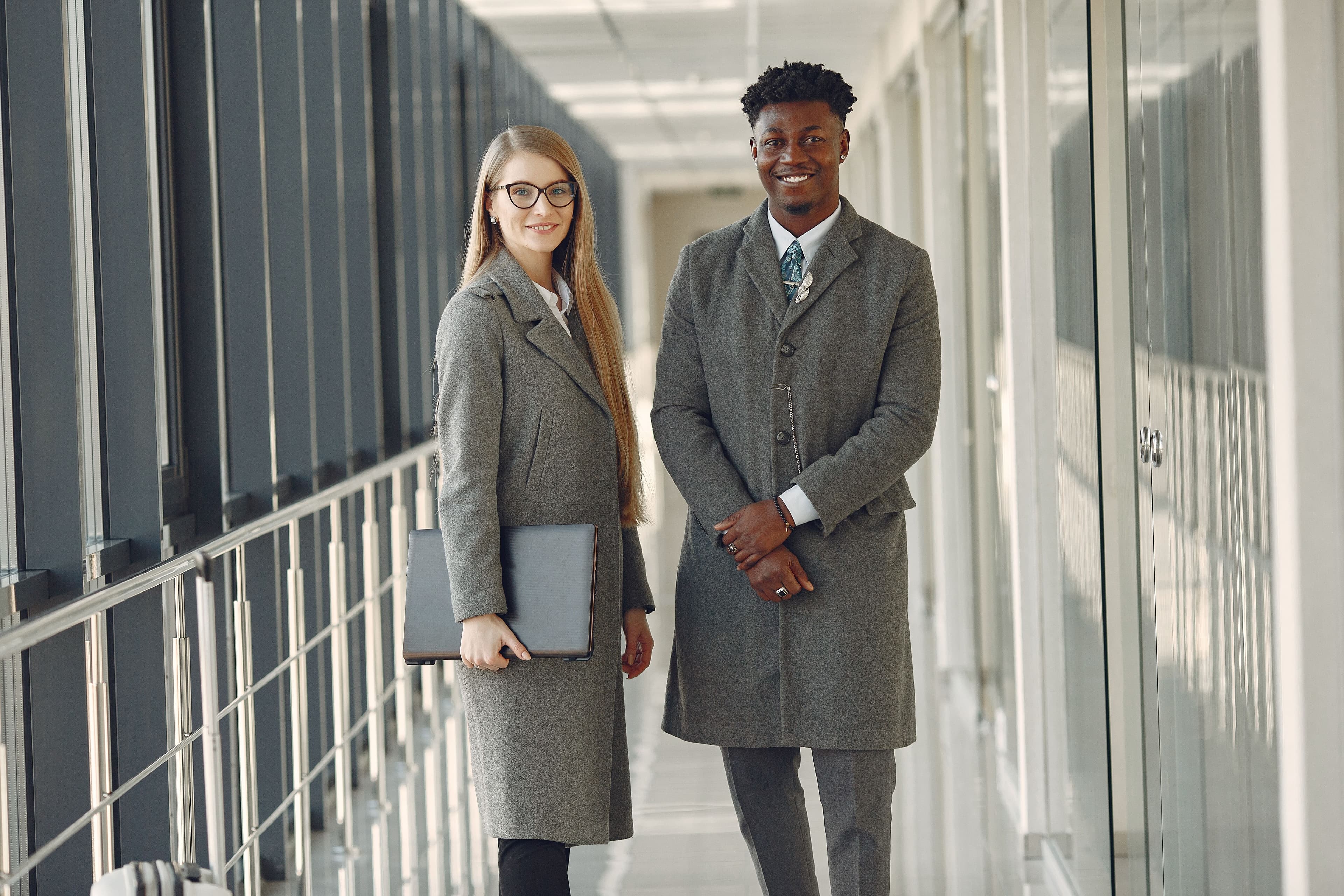 Two founders standing together in a bright modern office, smiling at the camera.